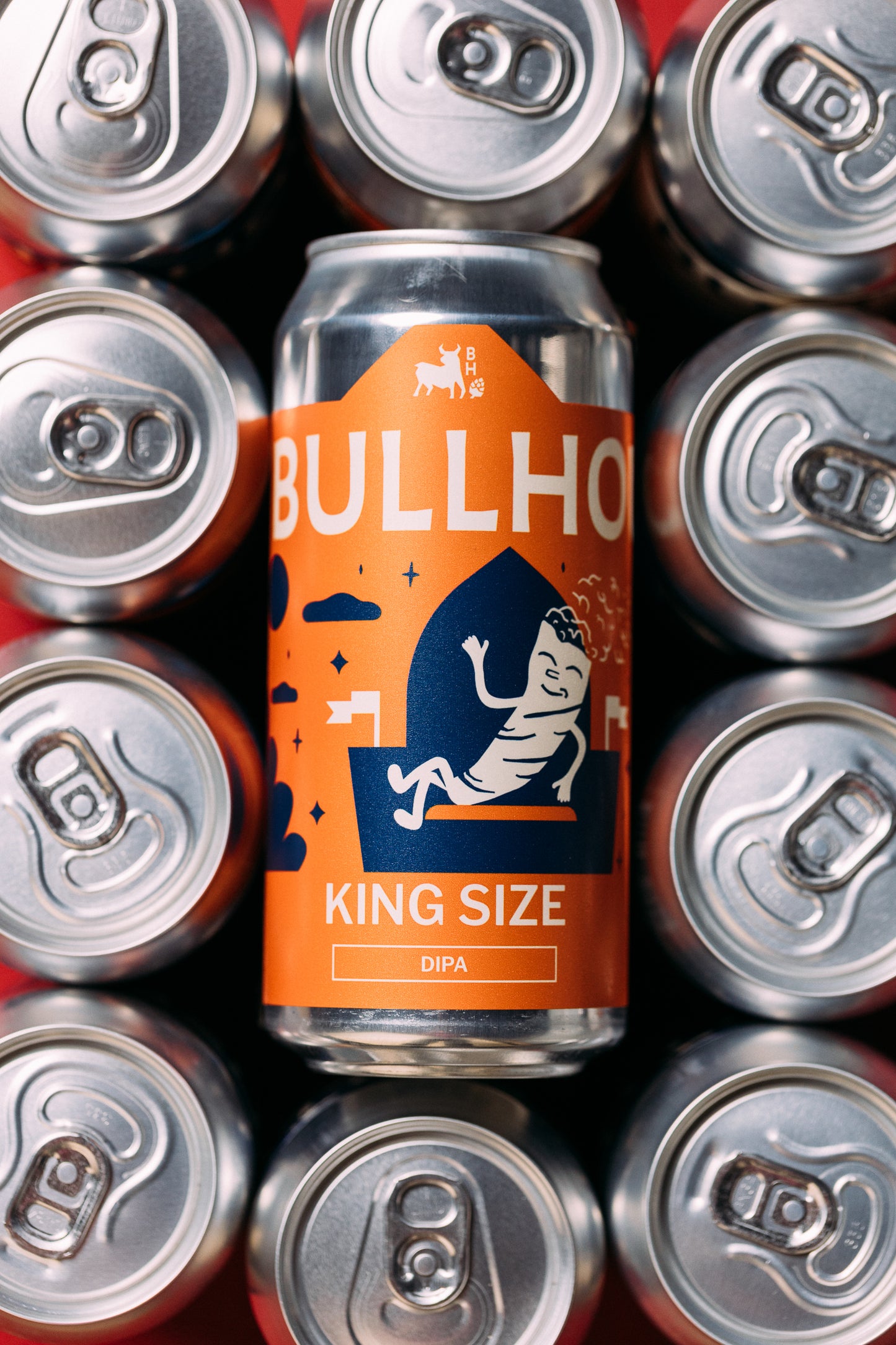 
                  
                    Bullhouse King Size beer can surrounded by silver beer cans on a red background
                  
                