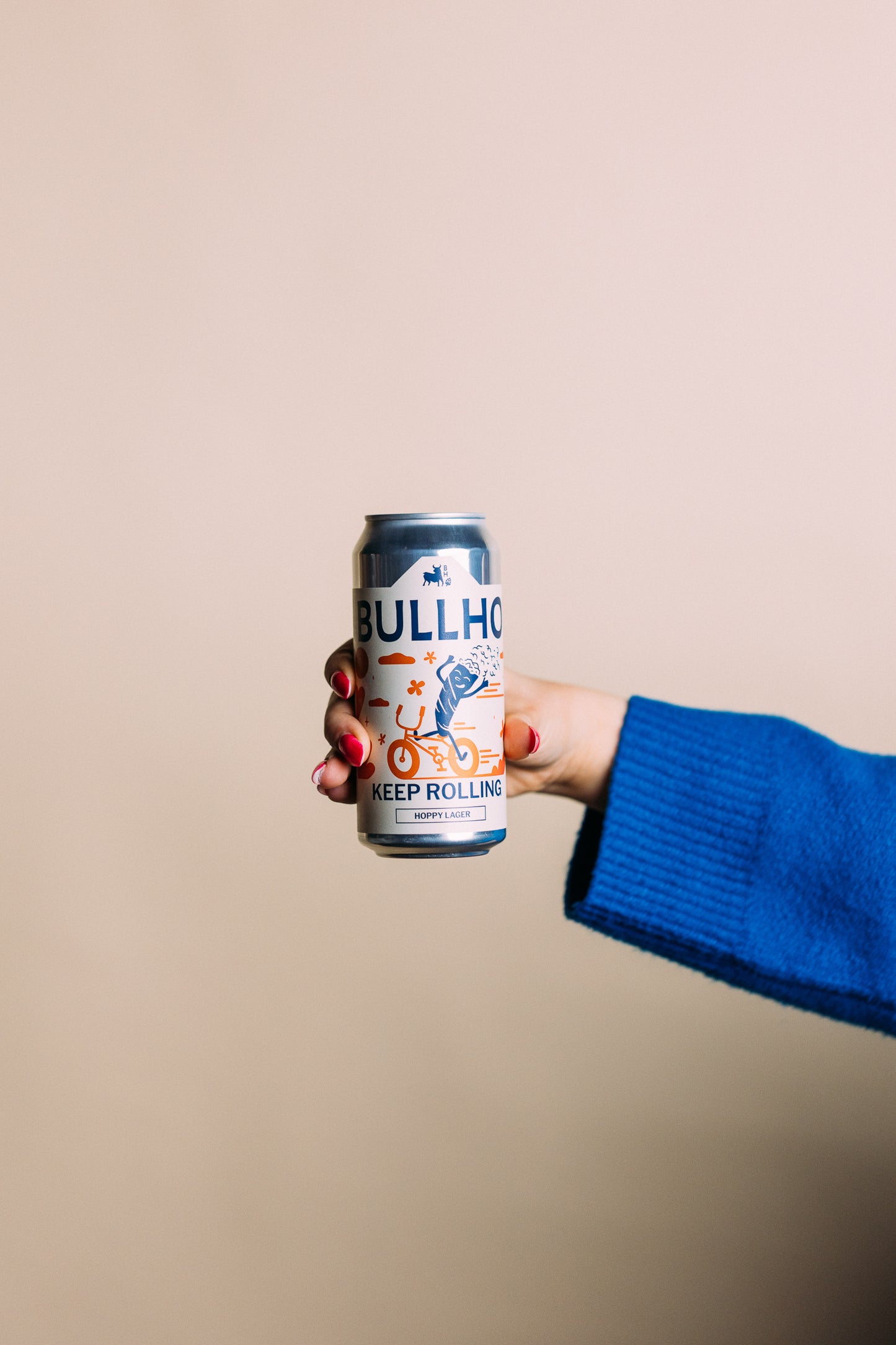 
                  
                    Hand holding a can of Bullhouse beer against a beige background
                  
                