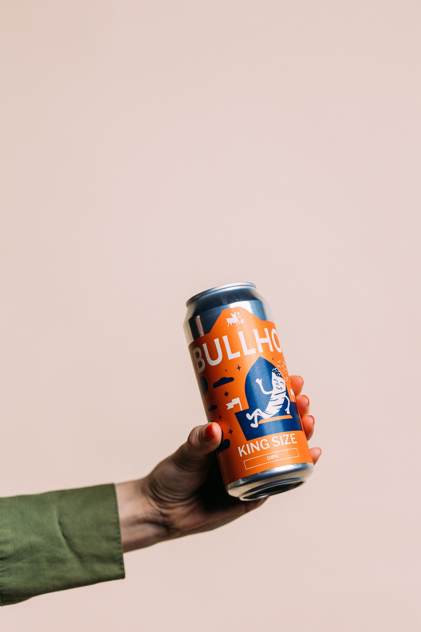 
                  
                    Hand holding a can of Bullhouse beer King Size DIPA against a beige background
                  
                