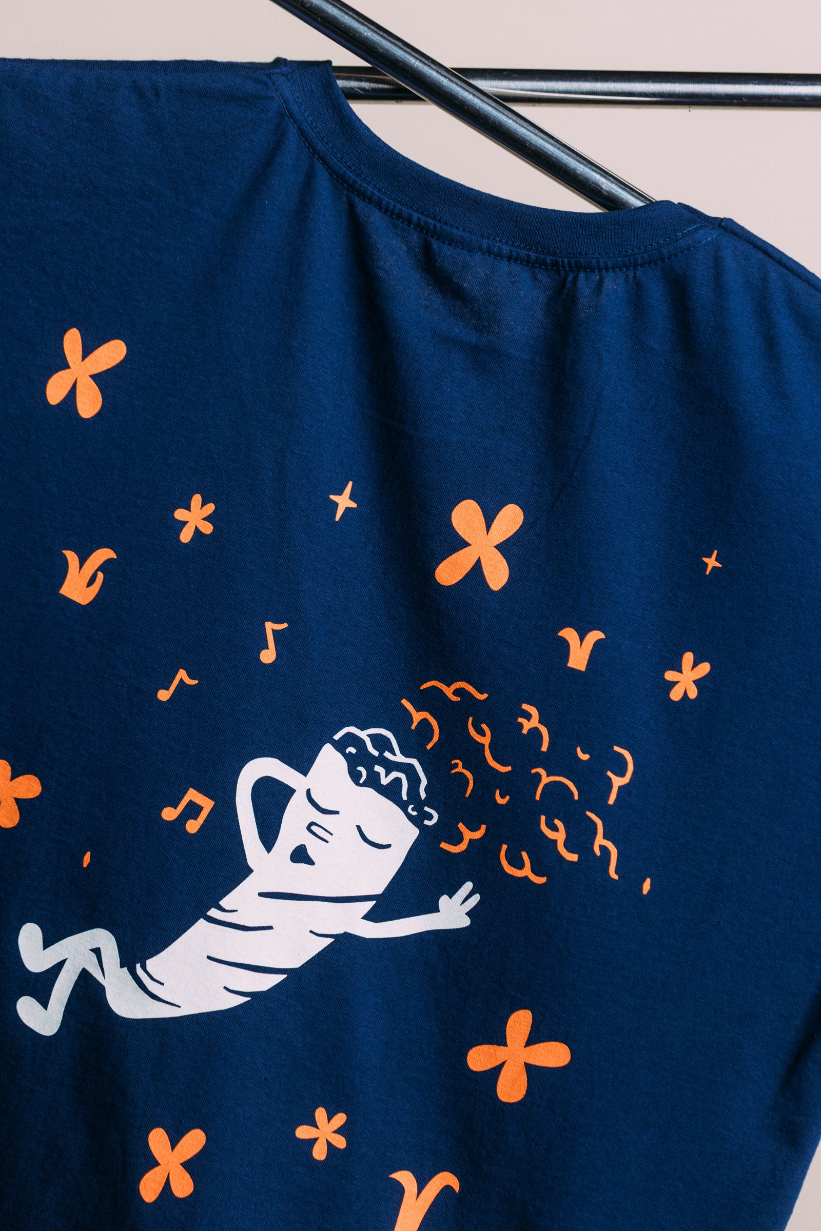 Navy blue t-shirt with white and orange graphic design on a hanger